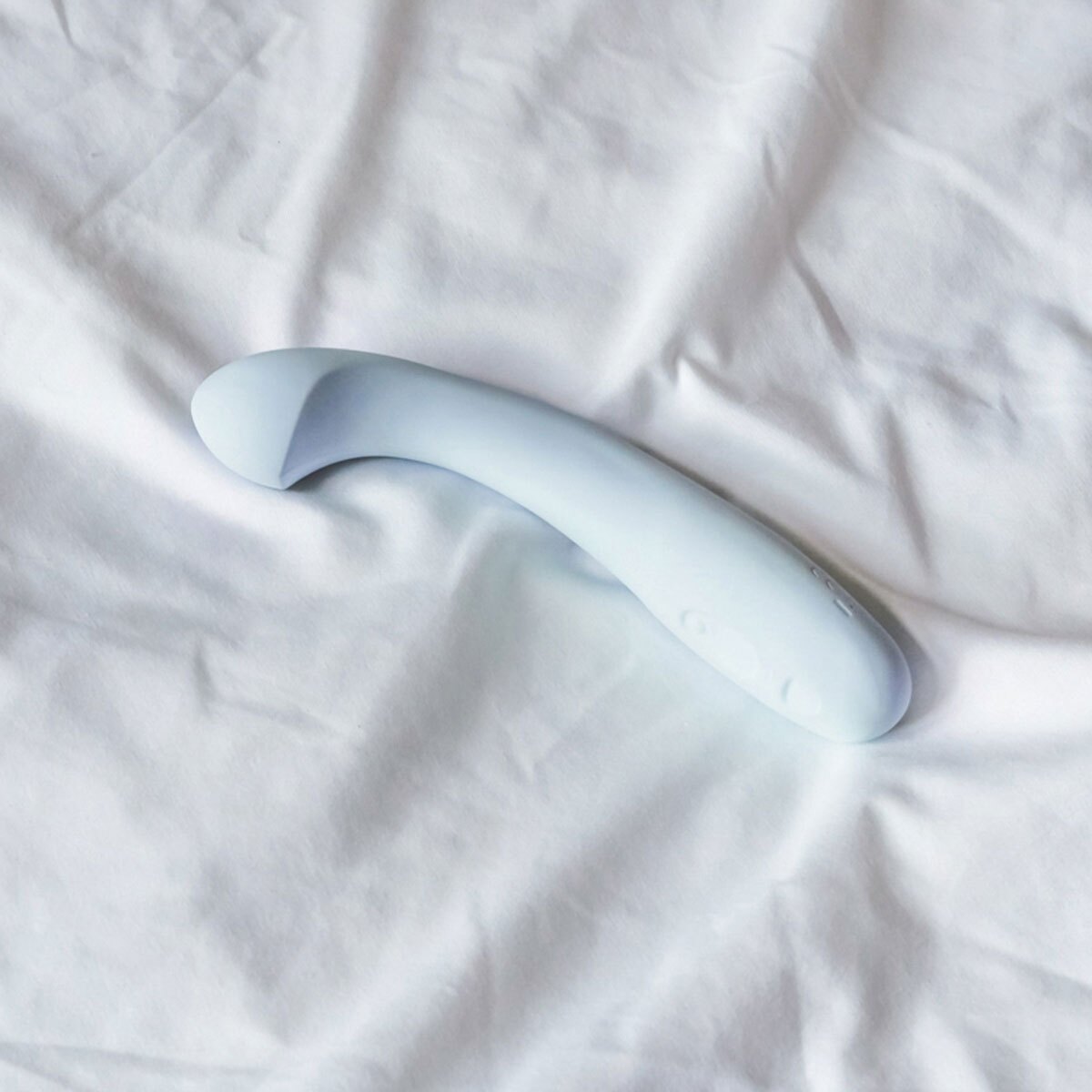 Lifestyle shot featuring the  Dame Products vibrator beside the bed