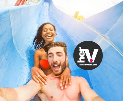 Couple laughing together on a water slide, symbolizing smooth, safe fun—just like the comfort of using anal lube from HerVibrators.com.